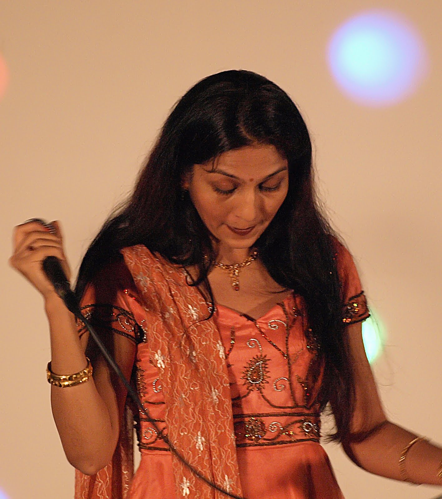 A woman in an orange sari, singing