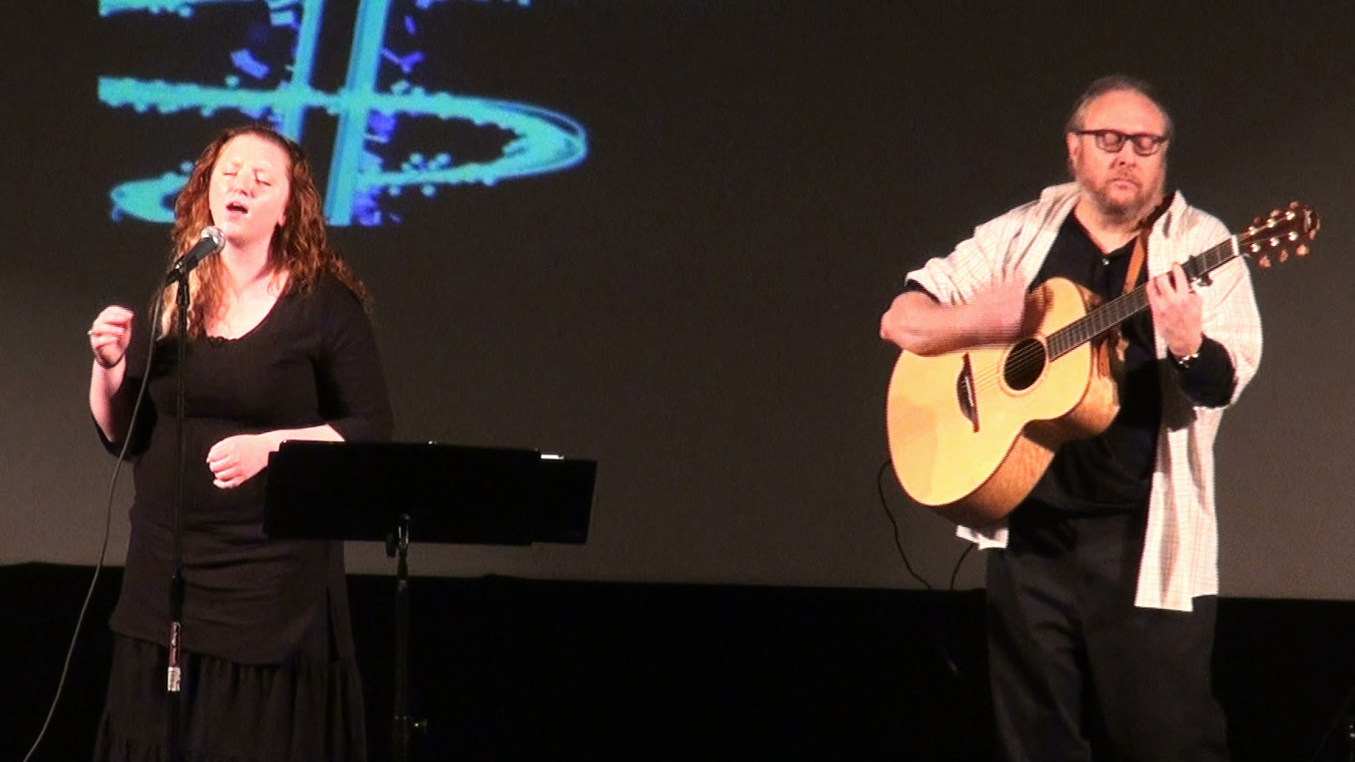 A woman singing while a guitarist accompanies her