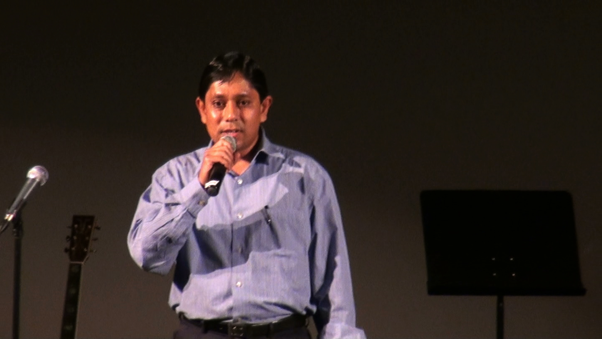 A man in a lavender shirt singing