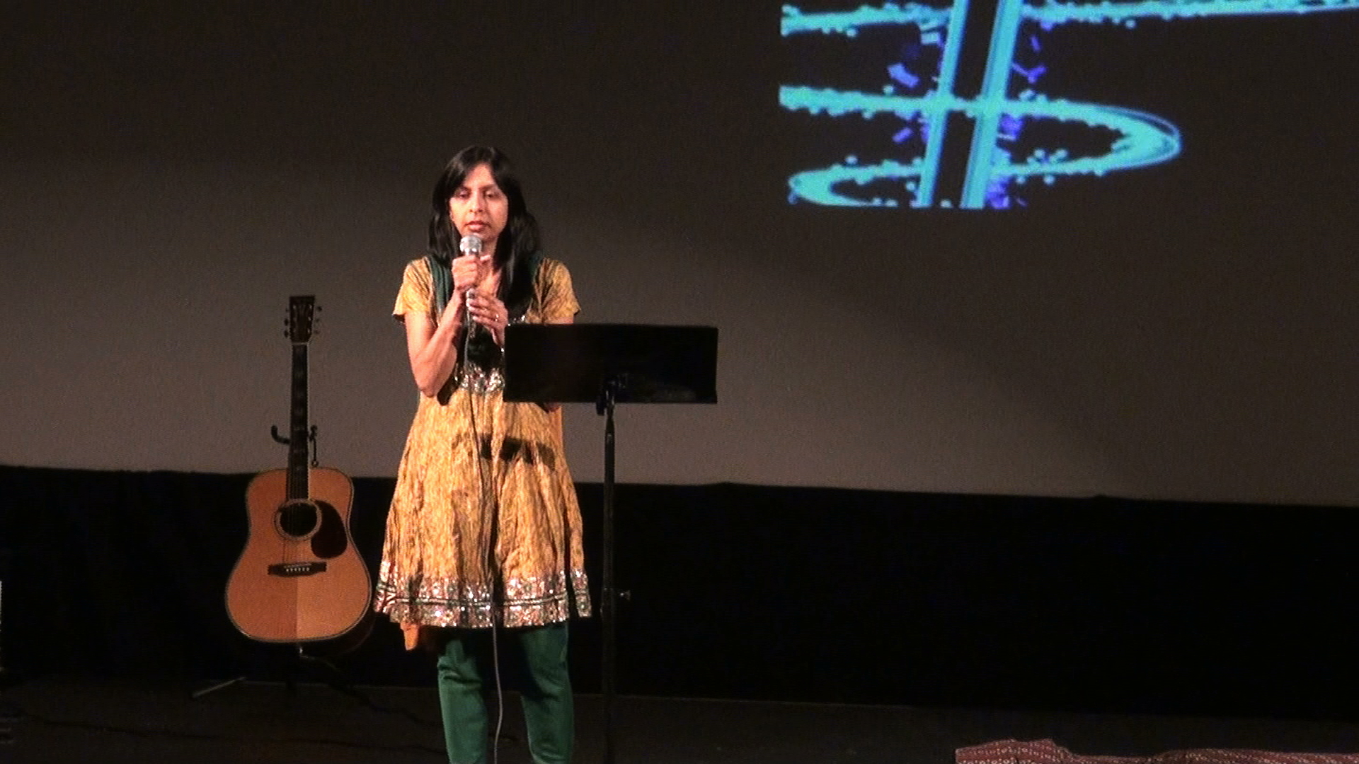 A woman singing near a guitar