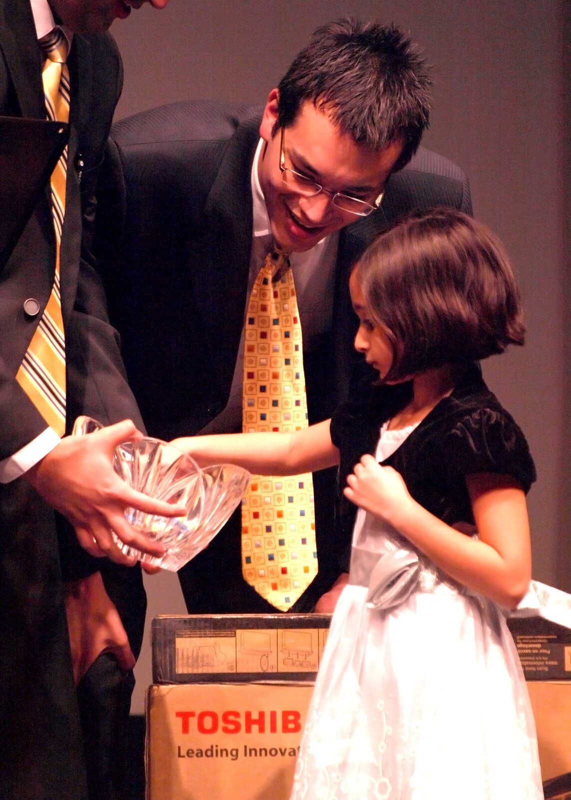 A man in a suit presenting an award to a young girl on stage