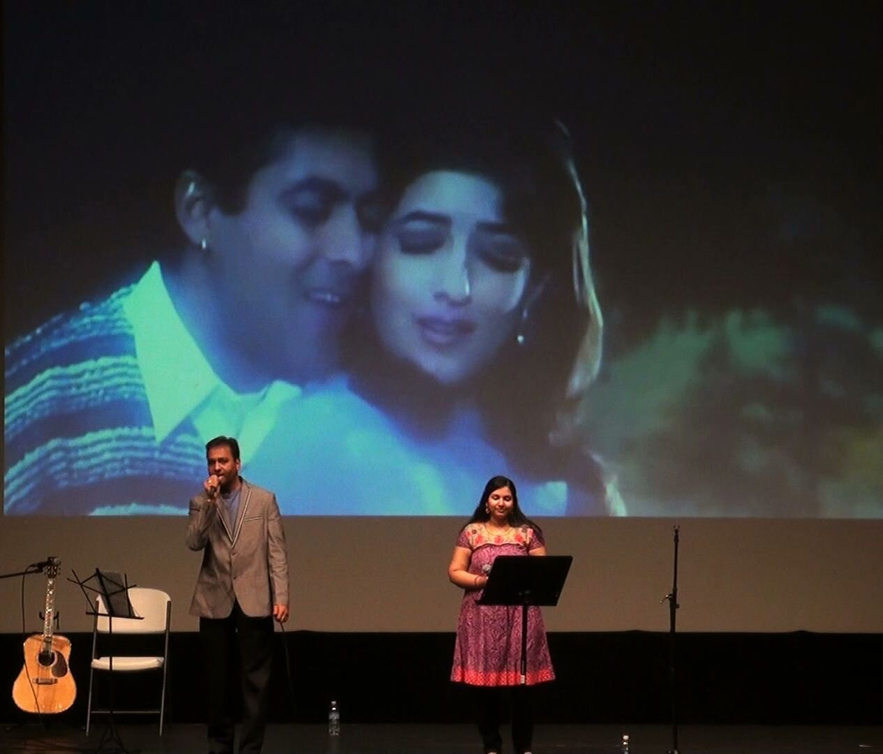 A performer singing in front of a projected film clip
