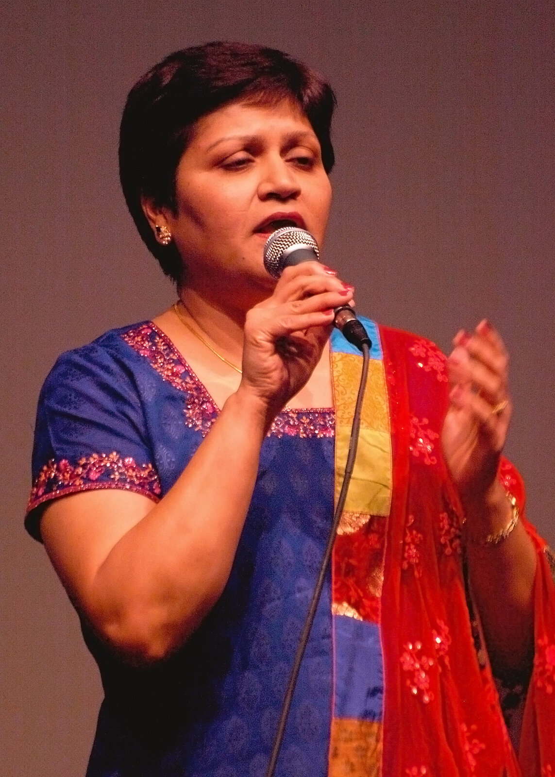 A woman in a red and orange outfit singing