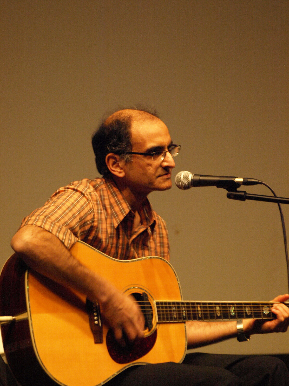 A man playing guitar close to the microphone