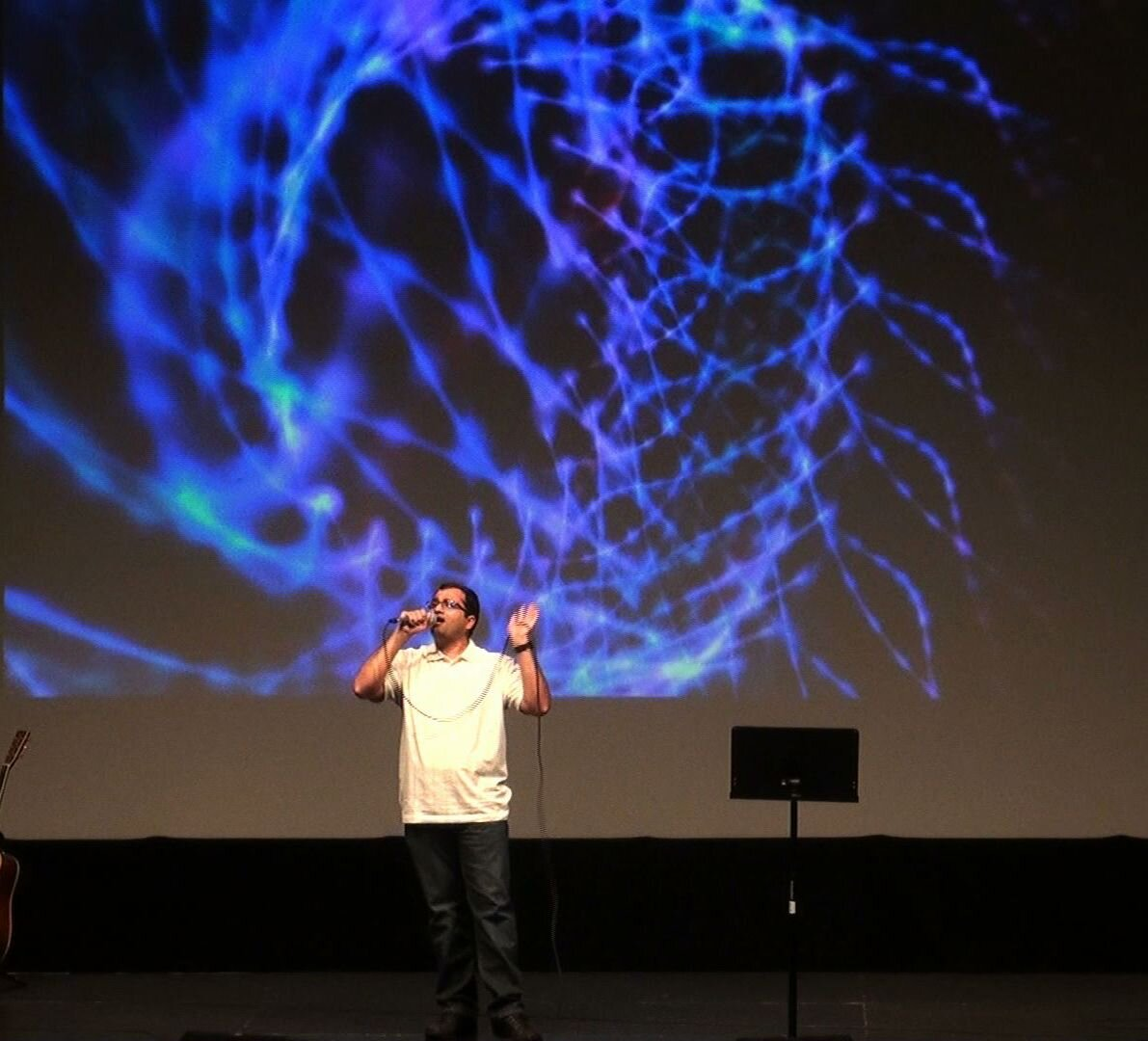 A man singing in front of a blue backdrop