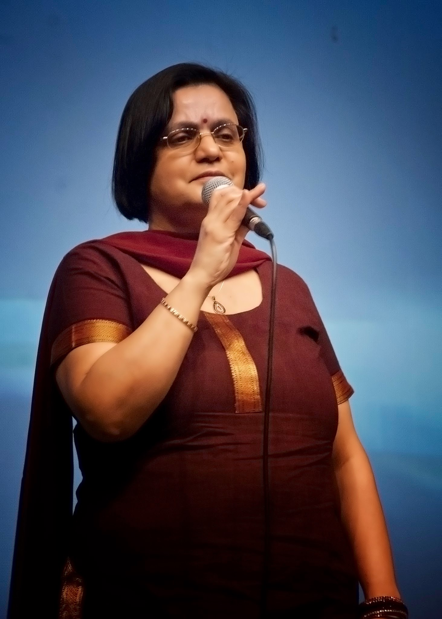 A woman in a maroon outfit singing