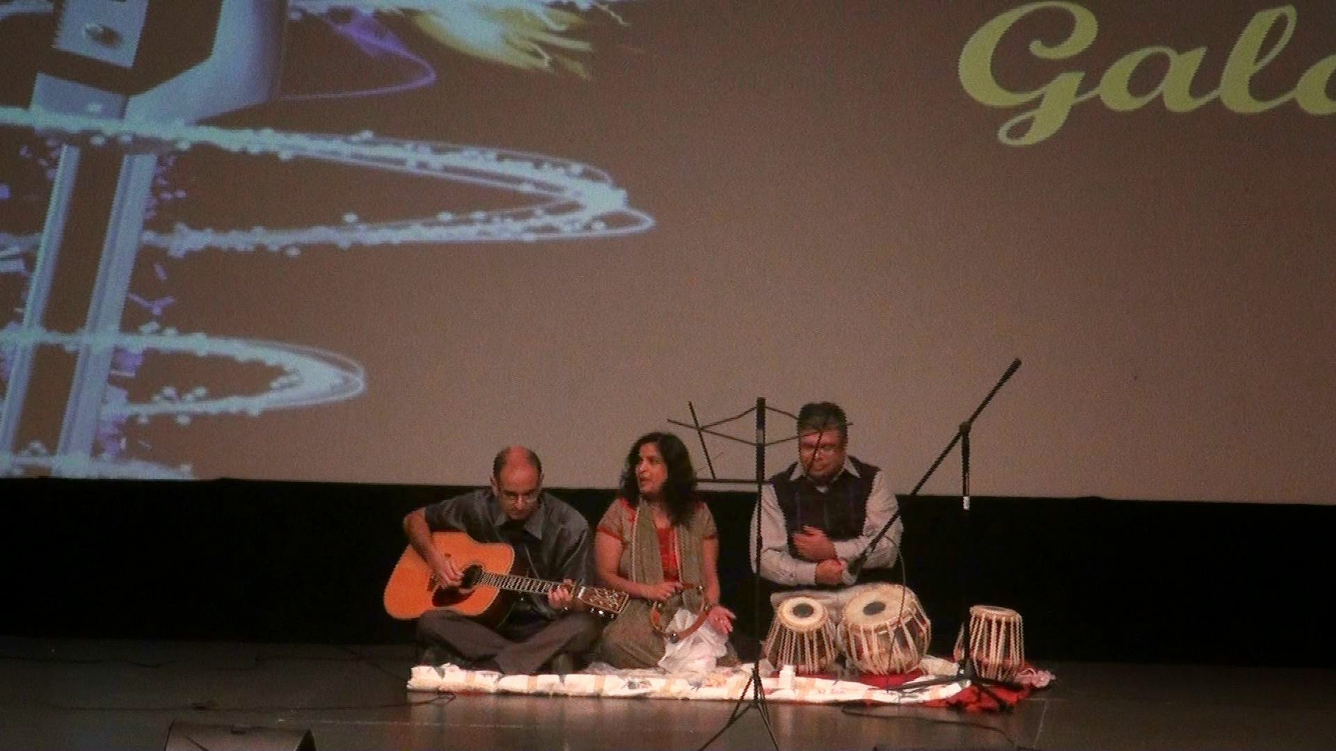 A guitarist and tabla player performing in front of the Gala backdrop