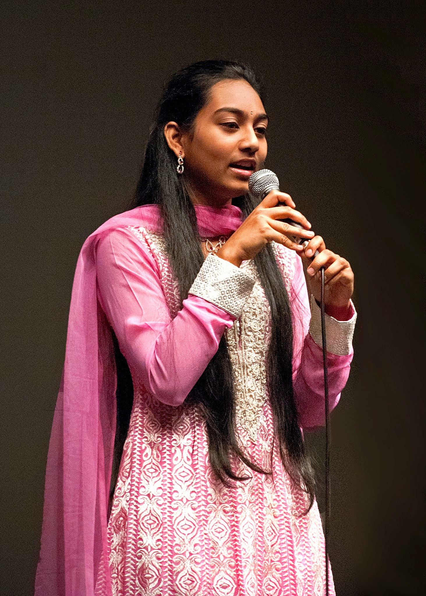 A woman in a pink outfit singing