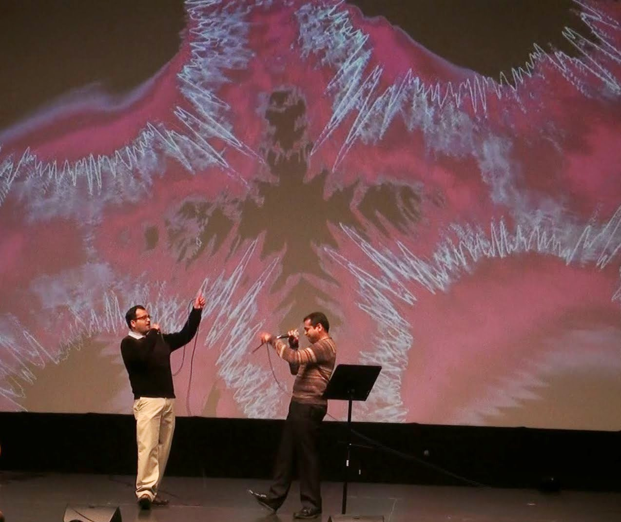 Two men singing together on stage