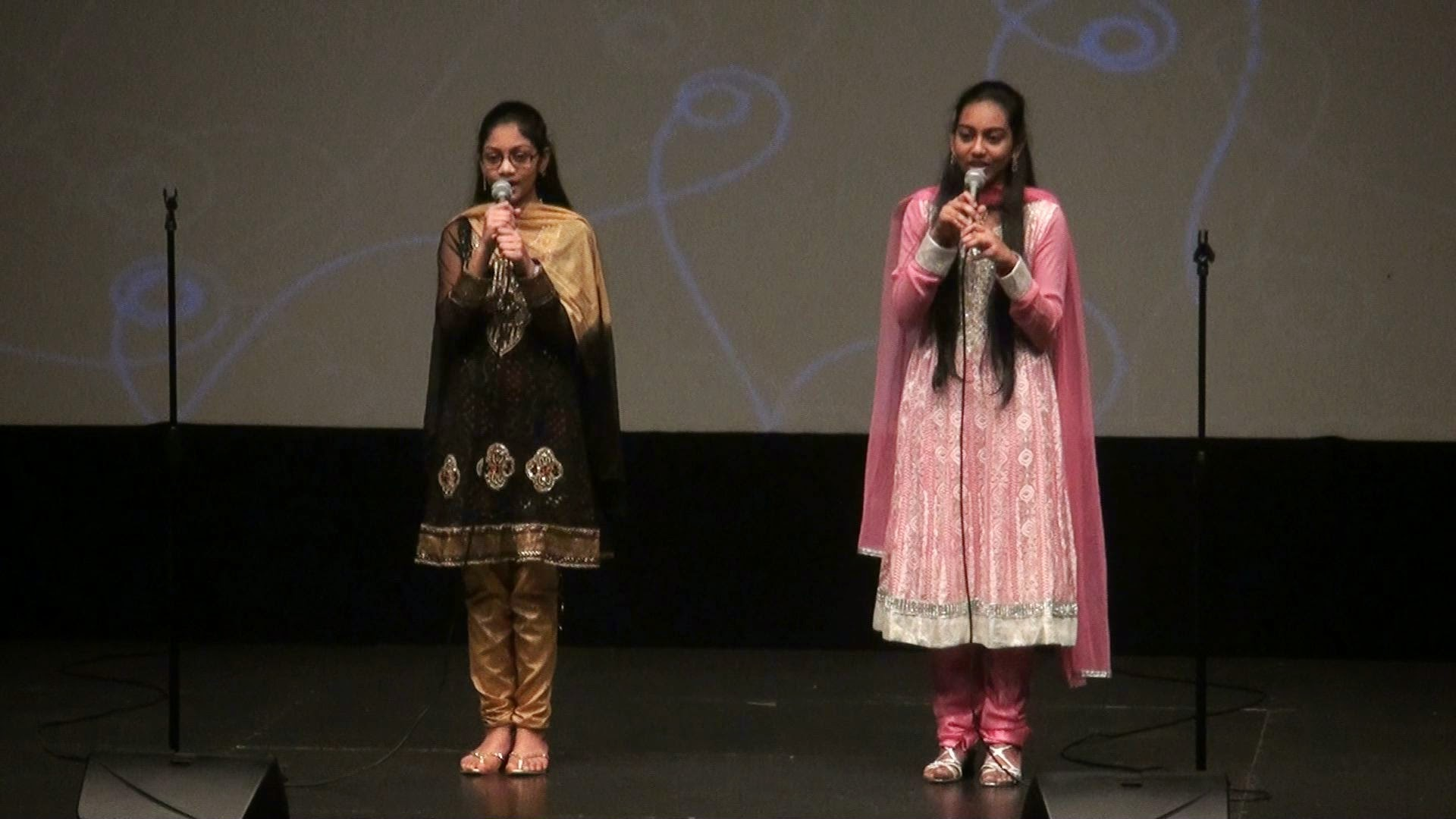 Two young girls singing a duet in matching outfits