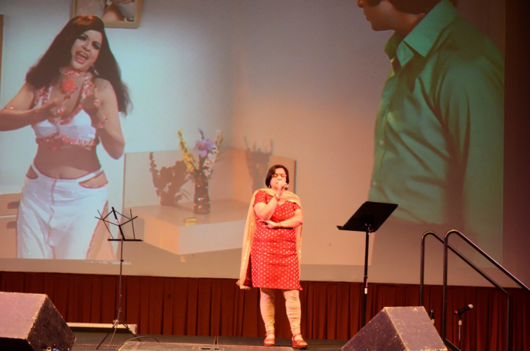 A woman and a man singing a duet, with a scene projected behind them