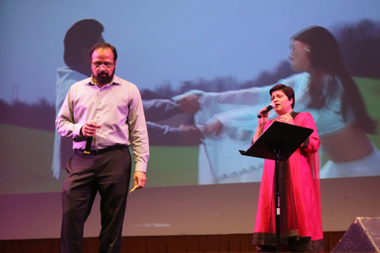 A man singing with a projected image of a woman behind him