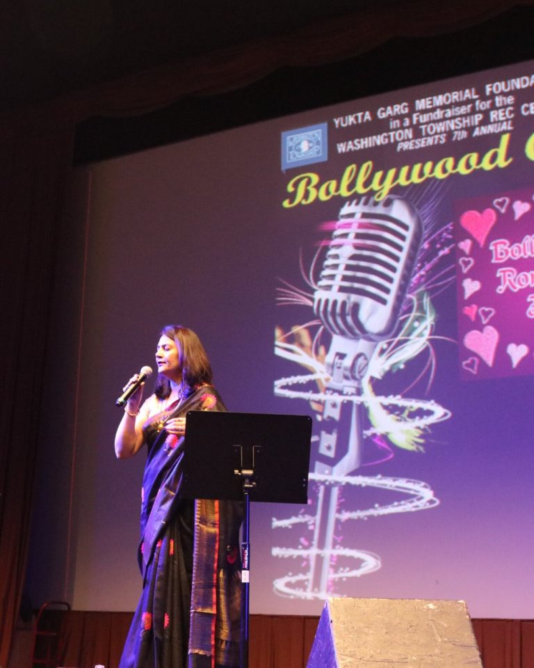 A woman singing in front of the Bollywood Gala screen