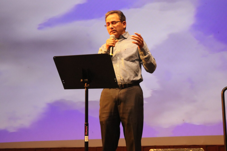 A man singing with a cloud backdrop projected behind him